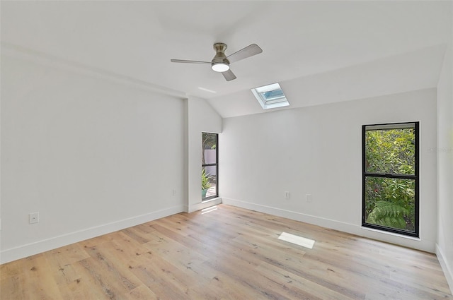 spare room featuring light hardwood / wood-style flooring, lofted ceiling with skylight, and ceiling fan