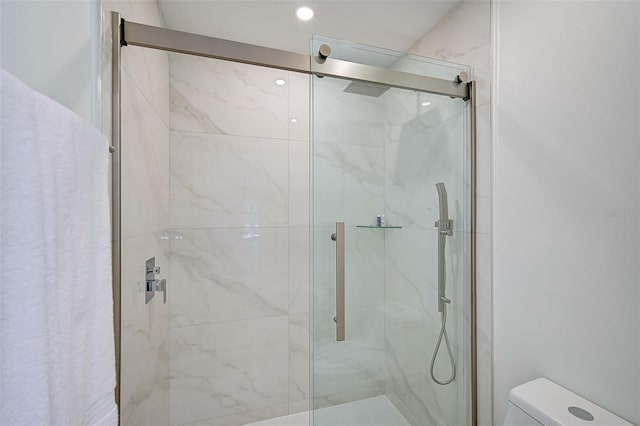 bathroom featuring toilet and a shower with shower door