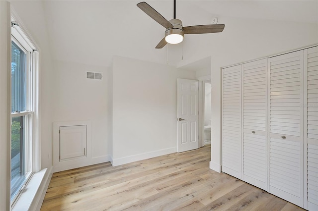 unfurnished bedroom with multiple windows, lofted ceiling, a closet, and light hardwood / wood-style flooring