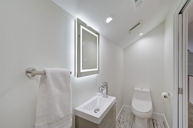 bathroom with vanity, lofted ceiling, and toilet