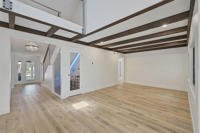 unfurnished living room with beamed ceiling, a chandelier, french doors, and light wood-type flooring