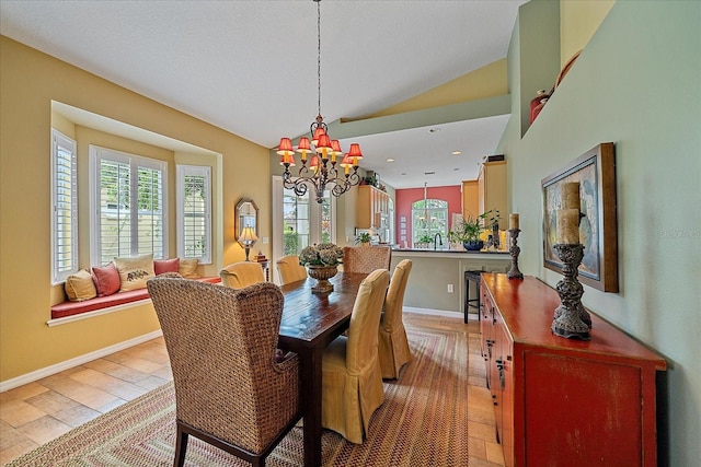 dining room with a notable chandelier, sink, vaulted ceiling, and light wood-type flooring