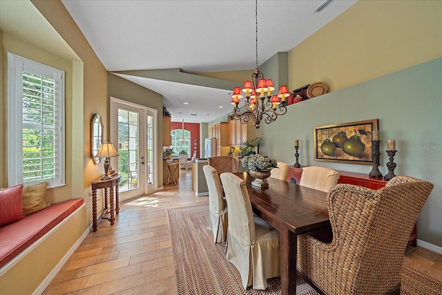 dining space with plenty of natural light, a chandelier, lofted ceiling, and light hardwood / wood-style flooring