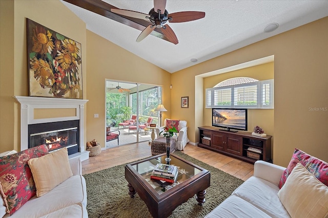 living room with lofted ceiling, a healthy amount of sunlight, light wood-type flooring, and a textured ceiling