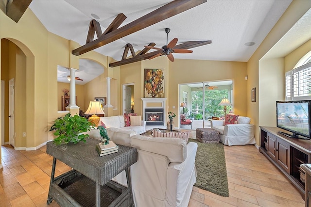 living room featuring high vaulted ceiling, ceiling fan, light hardwood / wood-style floors, a textured ceiling, and beam ceiling