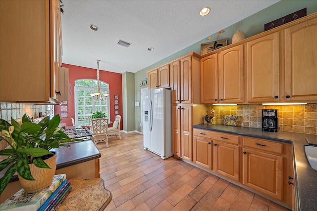 kitchen with fridge with ice dispenser, a notable chandelier, pendant lighting, a textured ceiling, and decorative backsplash