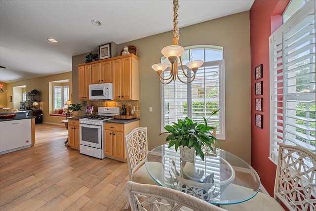 kitchen featuring pendant lighting, white appliances, a wealth of natural light, and a notable chandelier