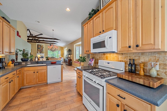 kitchen featuring sink, kitchen peninsula, vaulted ceiling, white appliances, and light wood-type flooring