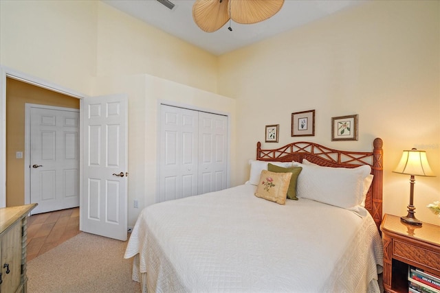 carpeted bedroom with ceiling fan, a closet, and a high ceiling