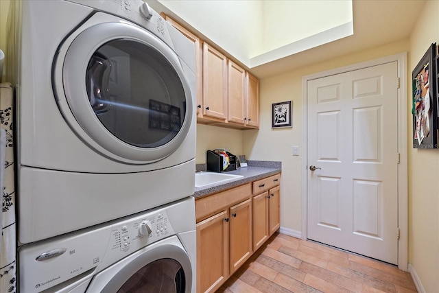 laundry room featuring sink, cabinets, stacked washer and clothes dryer, and light wood-type flooring