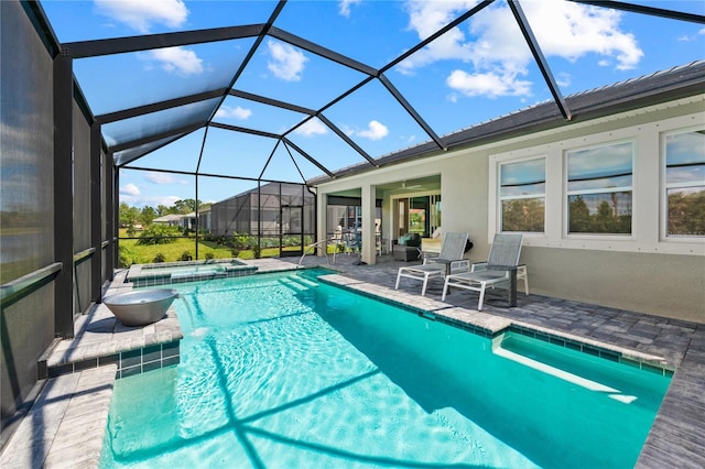 view of pool featuring glass enclosure, ceiling fan, a patio area, and an in ground hot tub