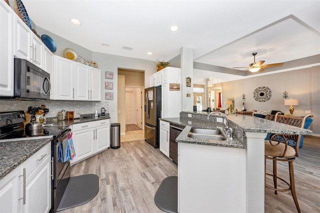 kitchen with a breakfast bar, appliances with stainless steel finishes, white cabinetry, and sink