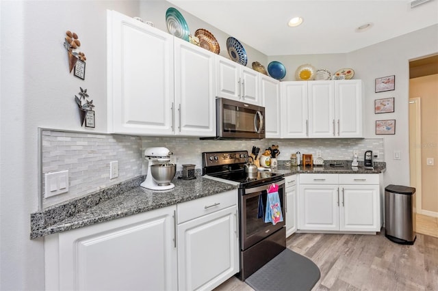 kitchen featuring decorative backsplash, appliances with stainless steel finishes, light wood-type flooring, and white cabinetry