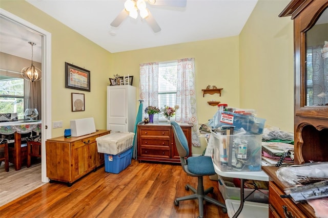 office space with ceiling fan with notable chandelier, a healthy amount of sunlight, and wood-type flooring