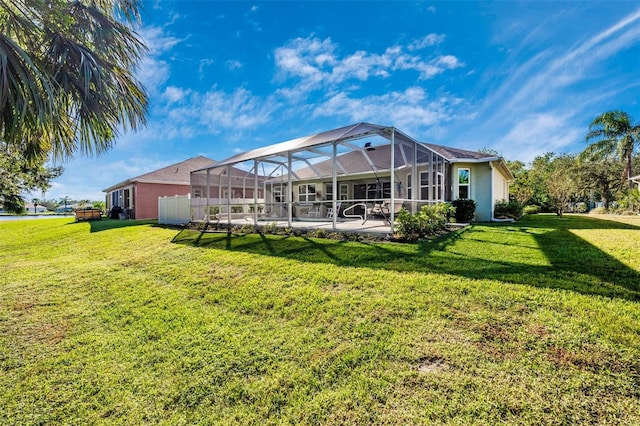 back of property with glass enclosure, a patio area, and a lawn