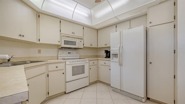 kitchen featuring cream cabinets, sink, light tile patterned floors, and white appliances