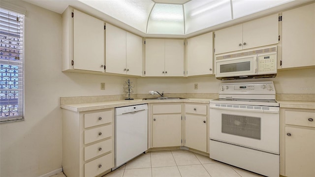 kitchen with white appliances, sink, light tile patterned floors, and cream cabinets