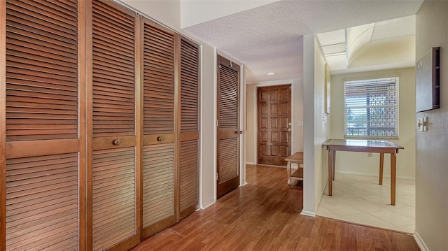 hall featuring light hardwood / wood-style floors and a textured ceiling