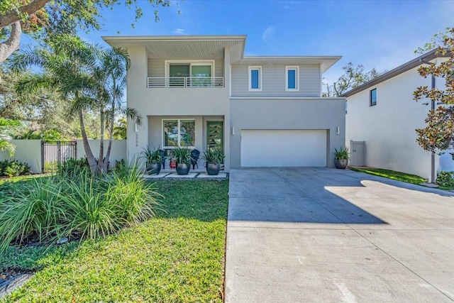 view of front facade featuring stucco siding, concrete driveway, fence, a balcony, and a garage