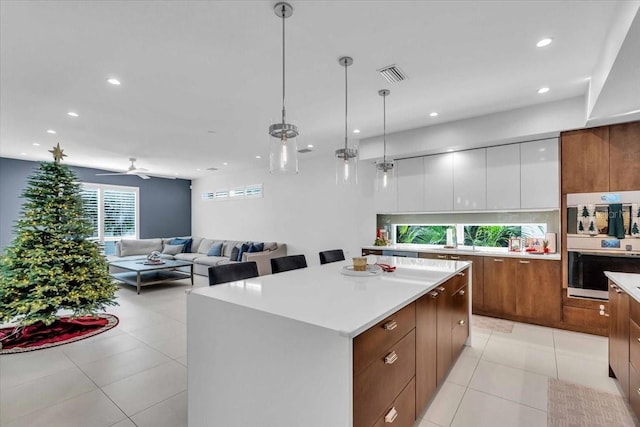 kitchen featuring white cabinetry, ceiling fan, a kitchen island, decorative light fixtures, and light tile patterned floors