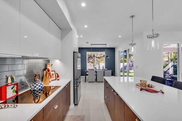 kitchen featuring stainless steel refrigerator, white cabinetry, a healthy amount of sunlight, and a notable chandelier