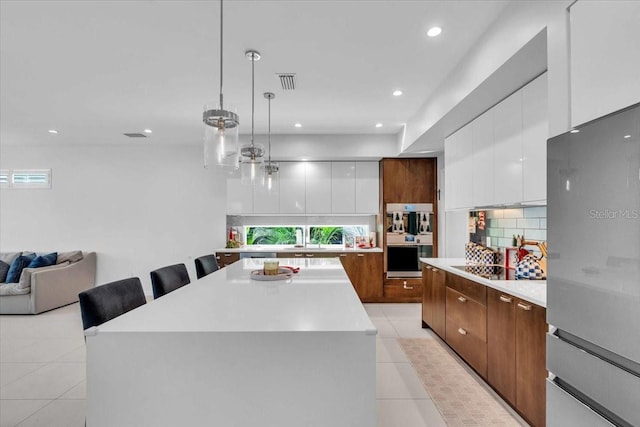 kitchen featuring pendant lighting, light tile patterned floors, a kitchen island, a kitchen bar, and white cabinetry