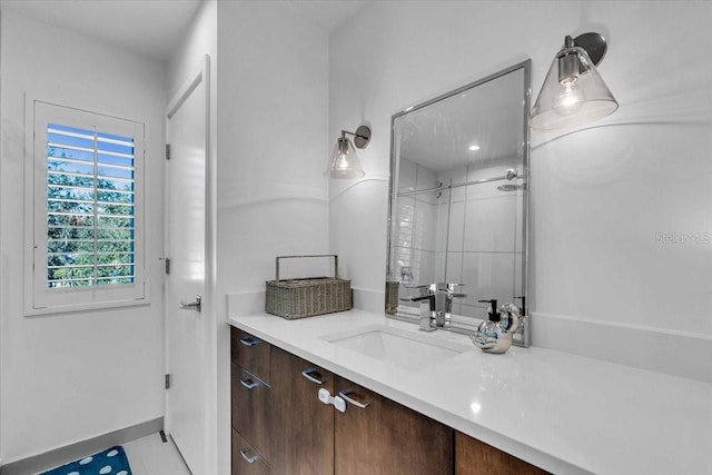 bathroom with a tile shower, vanity, and tile patterned floors