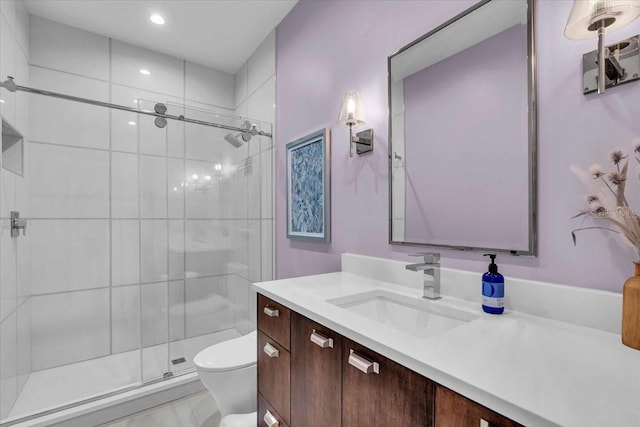 bathroom featuring vanity, a shower with shower door, and toilet