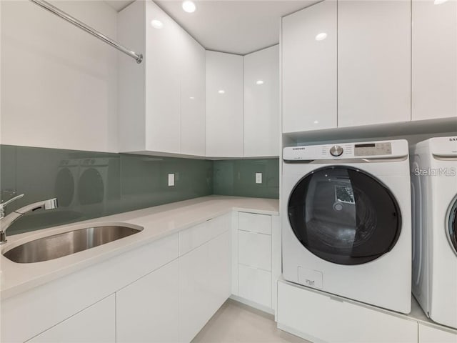 clothes washing area with cabinets, sink, and washing machine and clothes dryer