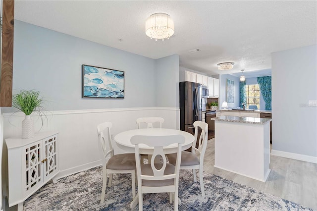 dining room featuring a chandelier, a textured ceiling, and light wood-type flooring