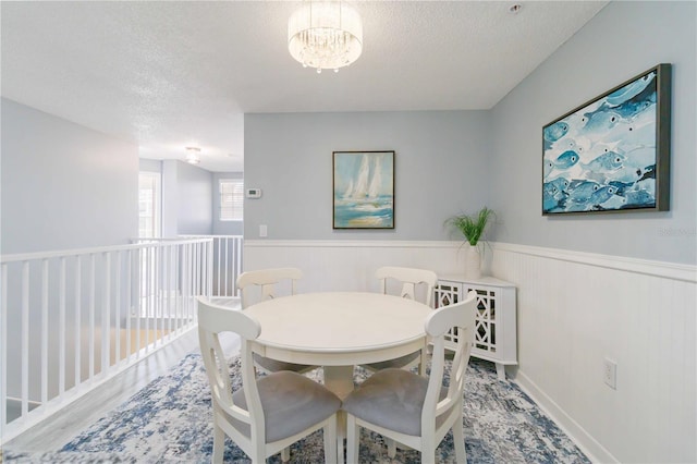 dining room featuring a chandelier, wood-type flooring, and a textured ceiling