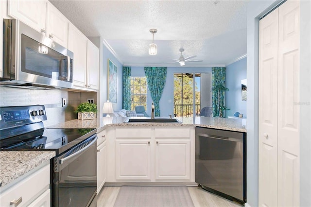 kitchen with kitchen peninsula, white cabinetry, sink, and appliances with stainless steel finishes