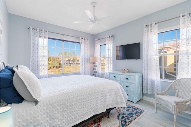 bedroom featuring multiple windows, ceiling fan, and light hardwood / wood-style floors