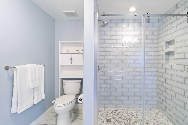 bathroom featuring a shower with door and toilet