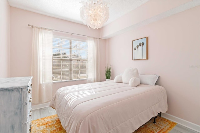 bedroom with hardwood / wood-style flooring, a textured ceiling, and a chandelier