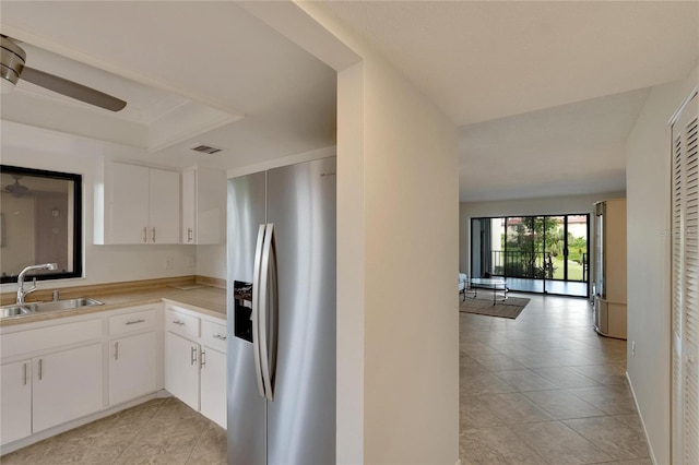 kitchen with white cabinets, stainless steel fridge, light tile patterned floors, and sink