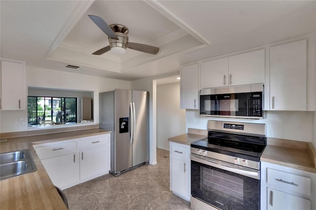 kitchen with a tray ceiling, ceiling fan, white cabinets, and stainless steel appliances