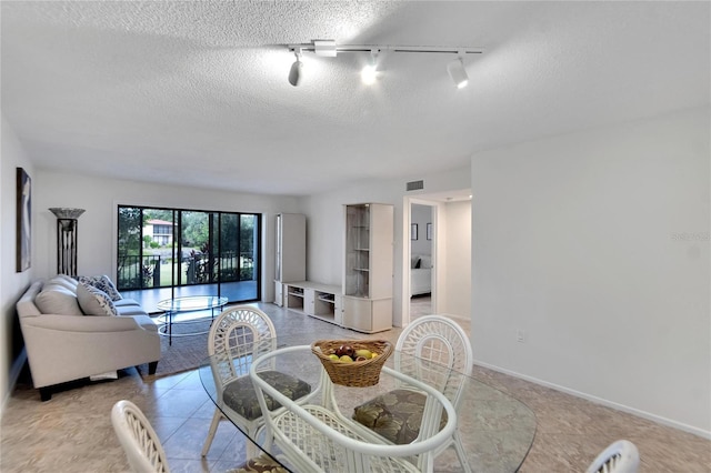 dining room with a textured ceiling, light tile patterned floors, and track lighting