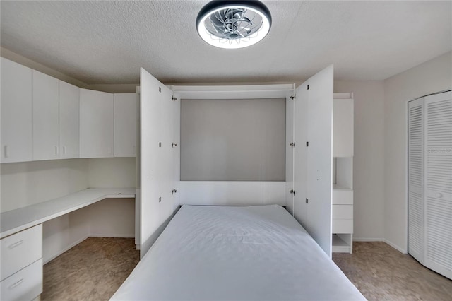 unfurnished bedroom featuring built in desk and a textured ceiling