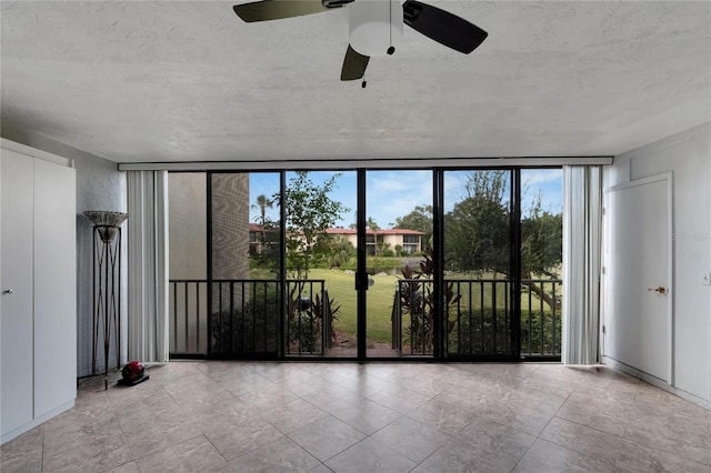 spare room featuring floor to ceiling windows, ceiling fan, and a textured ceiling