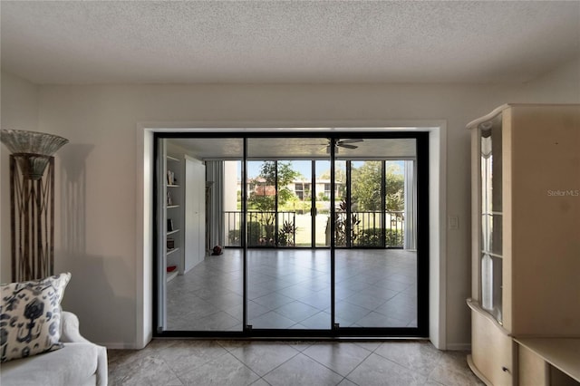 entryway featuring ceiling fan, light tile patterned flooring, and a textured ceiling