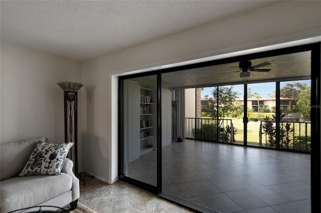 living room featuring ceiling fan, a wall of windows, a textured ceiling, and light tile patterned floors