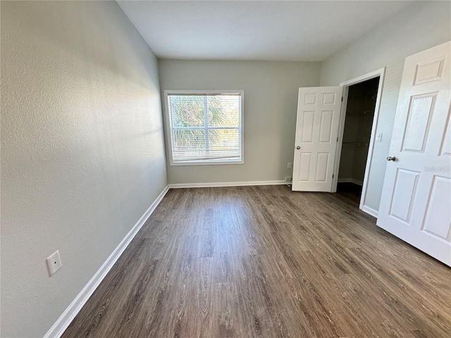 unfurnished bedroom with dark hardwood / wood-style floors, a spacious closet, and a closet