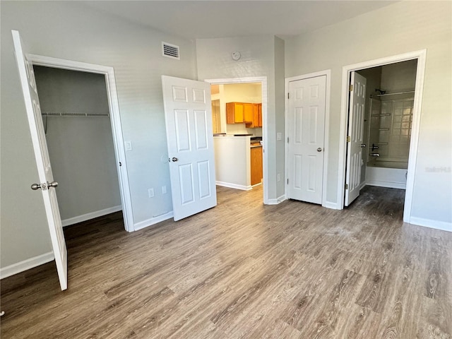 unfurnished bedroom with ensuite bathroom and light hardwood / wood-style flooring