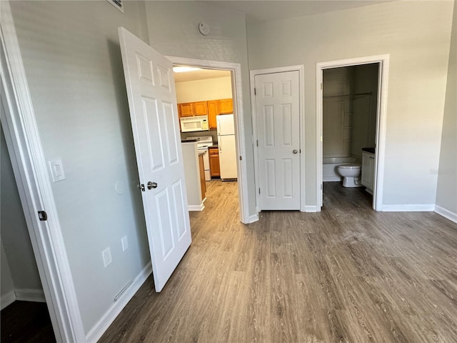 unfurnished bedroom with ensuite bathroom, light hardwood / wood-style floors, and white refrigerator