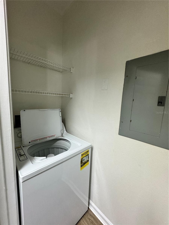 clothes washing area with electric panel, hardwood / wood-style floors, and washer / dryer