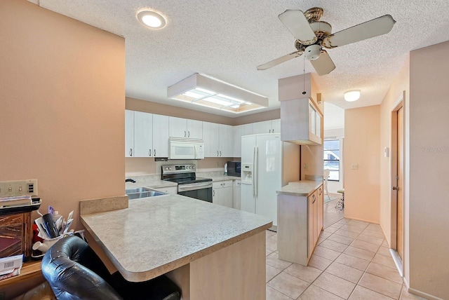 kitchen with white cabinetry, kitchen peninsula, a textured ceiling, white appliances, and a kitchen bar