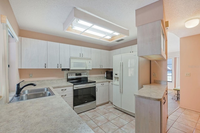 kitchen featuring white appliances, white cabinets, sink, light tile patterned floors, and a textured ceiling