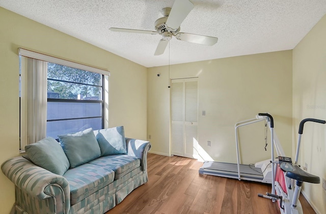 exercise area featuring a textured ceiling, ceiling fan, and dark hardwood / wood-style floors