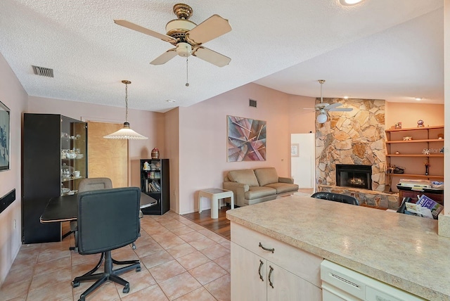 kitchen with vaulted ceiling, a fireplace, light tile patterned flooring, and a textured ceiling